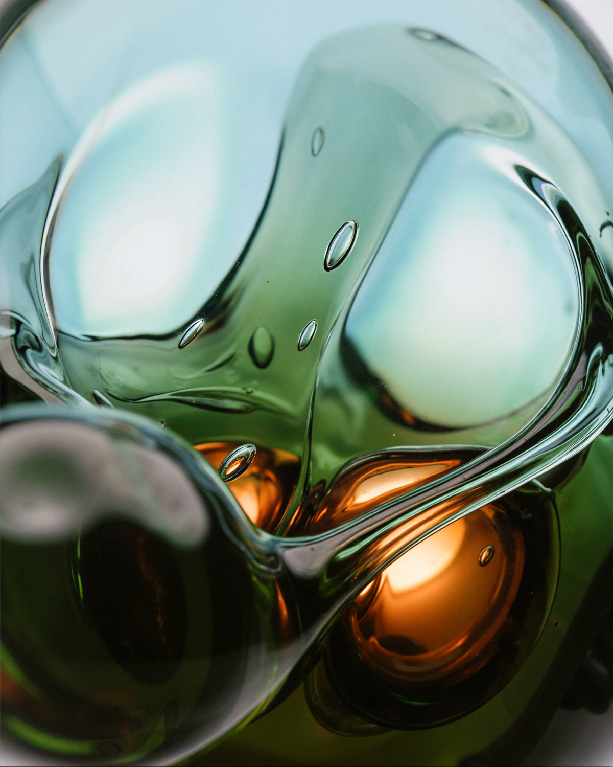 Liquid Light Engine — type specimen, green glass folding over amber cores, bubbles held in the mass